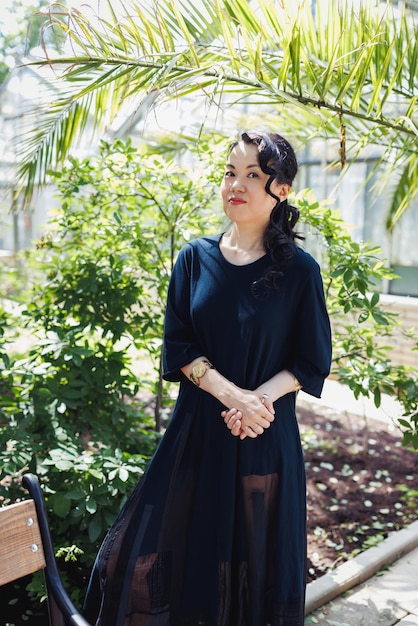 Happy middleaged Japanese woman in black casual dress in summer park