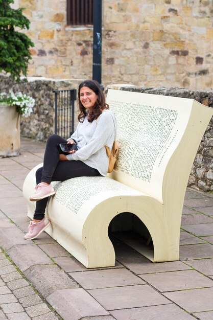 Фото Счастливая женщина средних лет наслаждается отдыхом и чтением на скамейке в форме книги