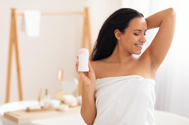 Happy Millennial Woman Holding Antiperspirant Stick Standing In Modern Bathroom
