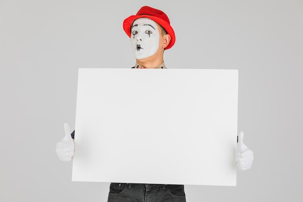 Happy MIME artist holding a blank white Board on a white background