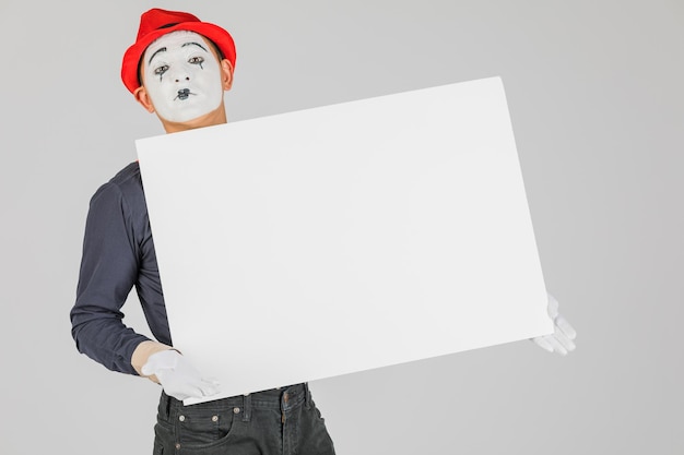 Happy MIME artist holding a blank white Board on a white background