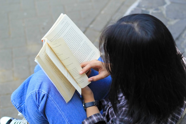 happy mindful young asian woman college student reading a book in the park education concept