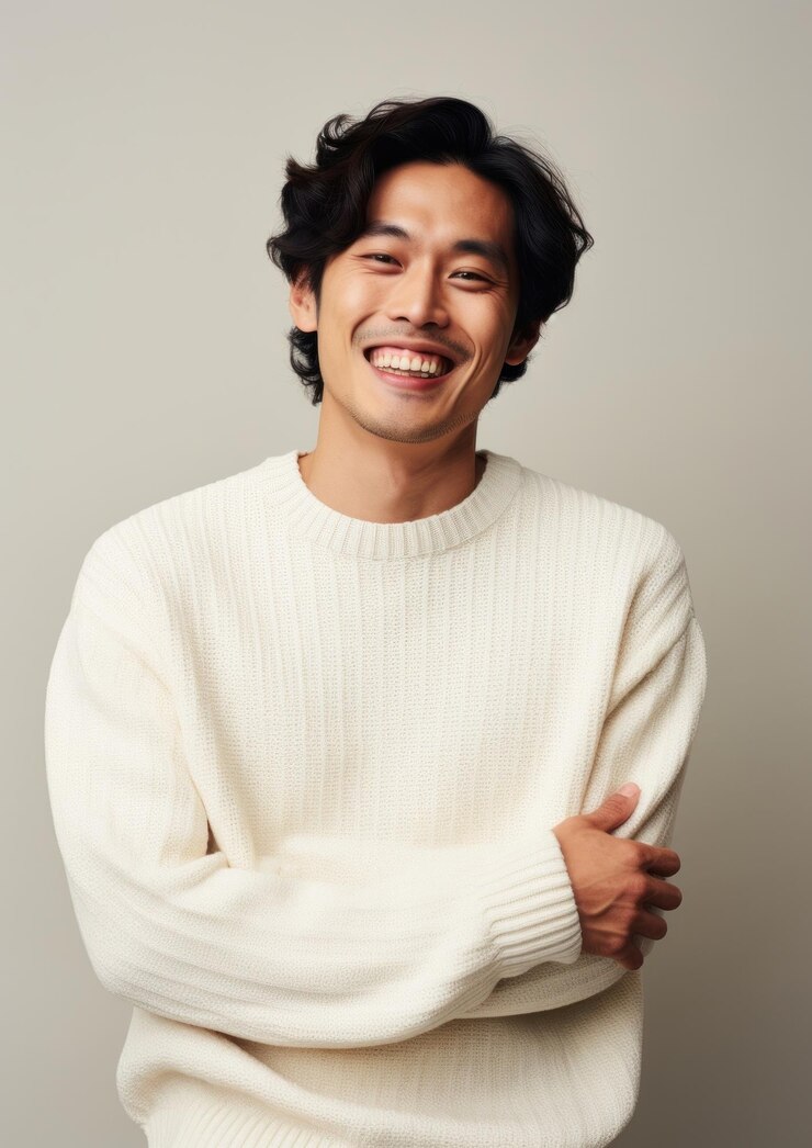 Photo 幸せな混血の韓国人男性クリーム色のセーターを着て笑顔で大人になっています