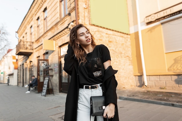 Happy model girl in fashion outfit walks on the street