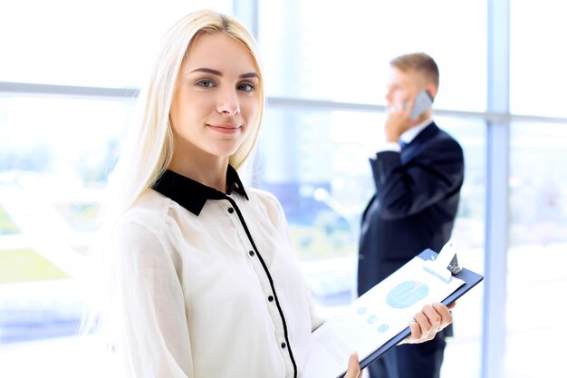 Happy modern business woman with financial report is in office hall.