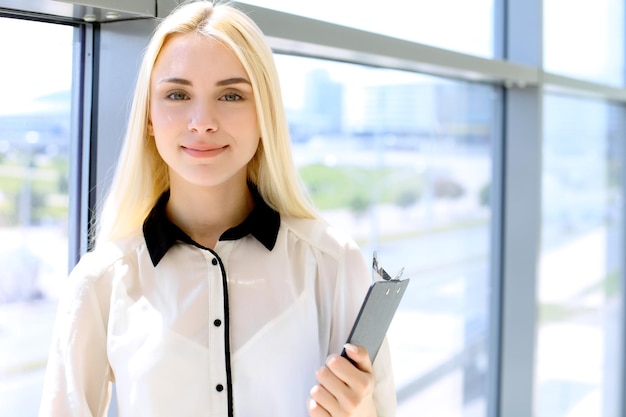 Happy modern business woman with financial report is in office hall.