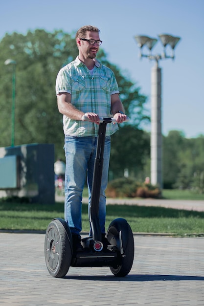 Happy modern man riding a mini hoverboard in the Park the concept of leisure