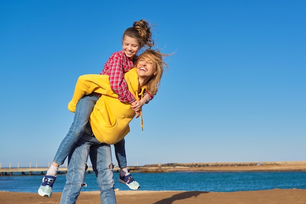 写真 砂浜でリラックスした海岸の幸せな母と娘の子供秋冬春シーズン