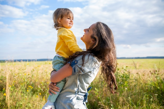 happy mom and baby play in the field in summer on a sunny summer day