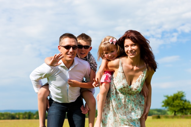 Foto felice mamma e papà che trasportano i loro bambini sulle spalle