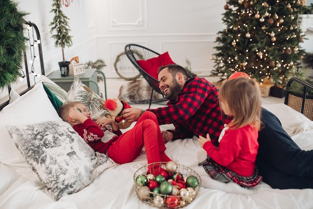 Happy mom dad and children lying down on bed at home