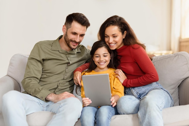 Happy mom dad and daughter using digital tablet at home