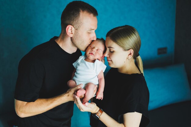 Happy mom and dad hold their newborn baby in their arms Young mother and father hug a newborn baby Young family and newborn baby at home