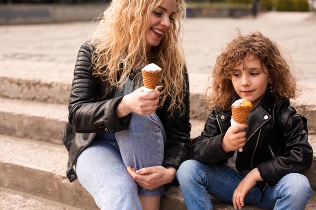 La mamma e la figlia felici tengono il gelato mentre camminano