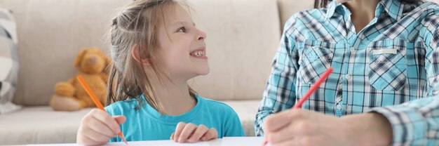 Mamma e figlia felici disegnano con le matite su carta