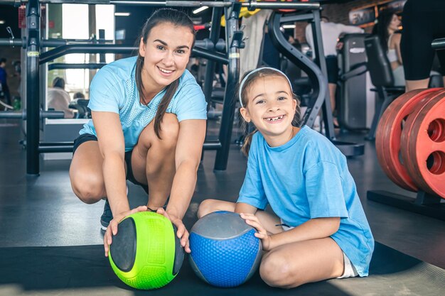 Happy mom and daughter in the gym with balls