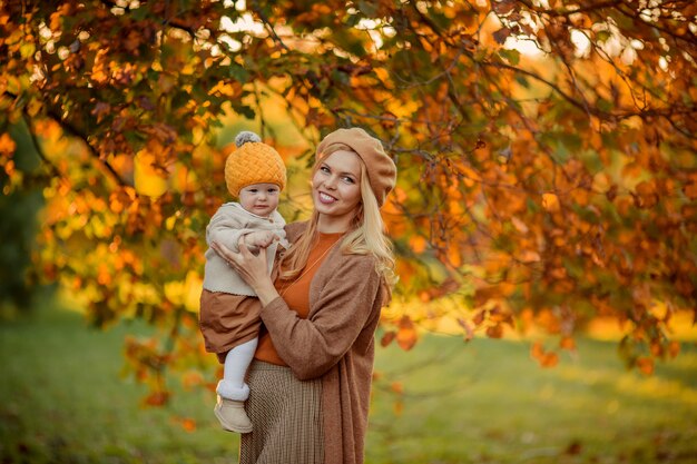 Happy mom and daughter in hats in the autumn park