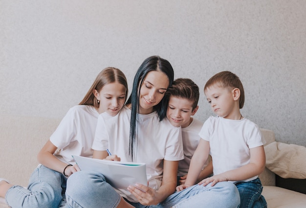 A happy mom draws a picture in an album sitting on the couch surrounded by her loving children.