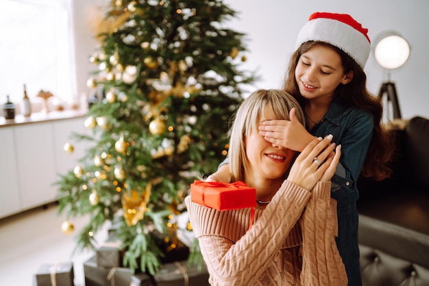 幸せなお母さんと彼女のかわいい娘の女の子は贈り物を交換します。メリークリスマス。