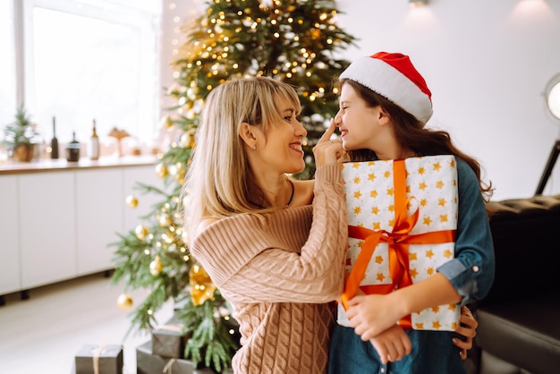 Happy mom and her cute daughter girl exchanging gifts Merry Christmas