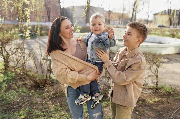 A happy mom plays with her two sons in a spring park