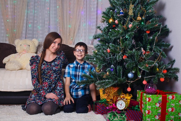 Happy mom and son at home celebrate Christmas New year mood Christmas tree and gifts