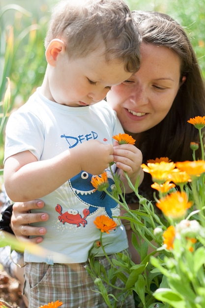 Happy mom with her son have fun playing, exploring nature and cuddling in the garden in summer