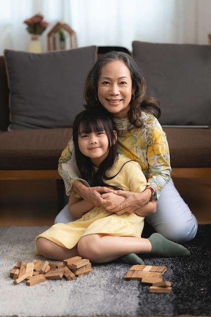 Photo happy moments of asian grandmother with her granddaughter playing jenga constructor leisure activities for children at home