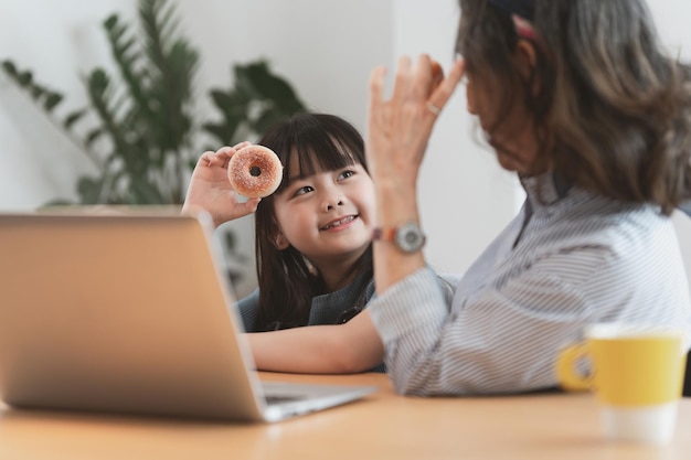 孫娘と一緒に話したり遊んだりするアジアの祖母の幸せな瞬間自宅で子供たちのための余暇活動