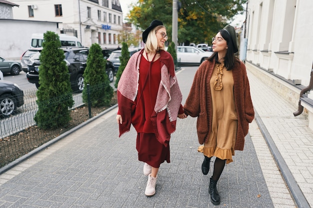 Happy moments with two stylish girls walking on street in the city. Closeup portrait, funny joyful attractive young women having fun, smiling, lovely moments, best friends, sisters.