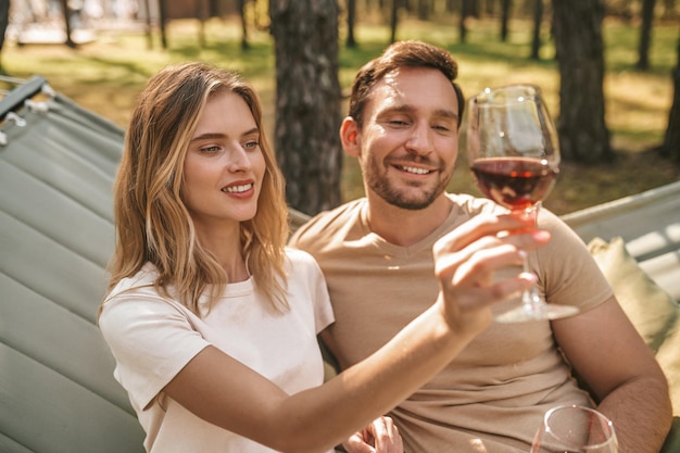 Happy moments. Young smiling couple holding glasses with wine and looking happy