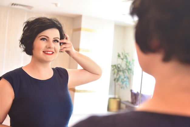 Happy Morning Attractive young fat woman looks at herself in the mirror and is happy with her beauty