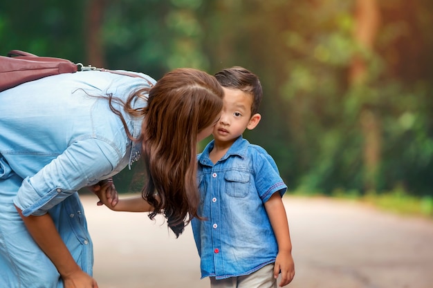 Happy mother and adorable little boy enjoying warm weather at beautiful park