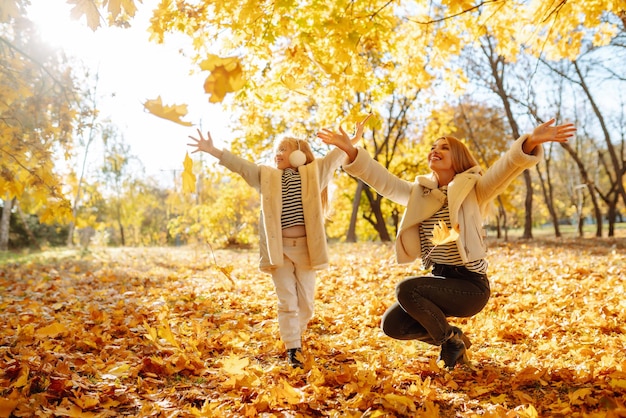 사진 행복한 엄마와 딸은 일몰 가을 공원에서 즐거운 시간을 보낸다 가족 산책 어린 시절 산책 휴식