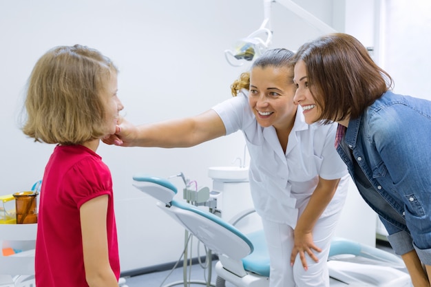 Happy mother and child in office with dentist doctor after dental treatment