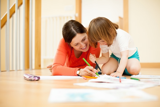 Felice madre e figlio che sketching al pavimento di parquet