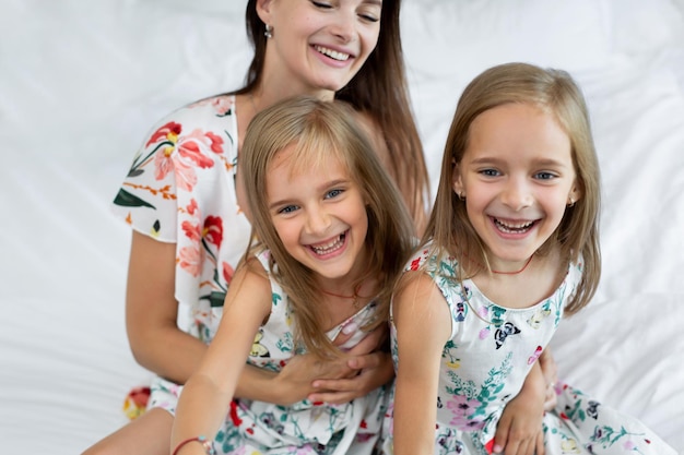 Happy mother and children of the twins sitting on the bed