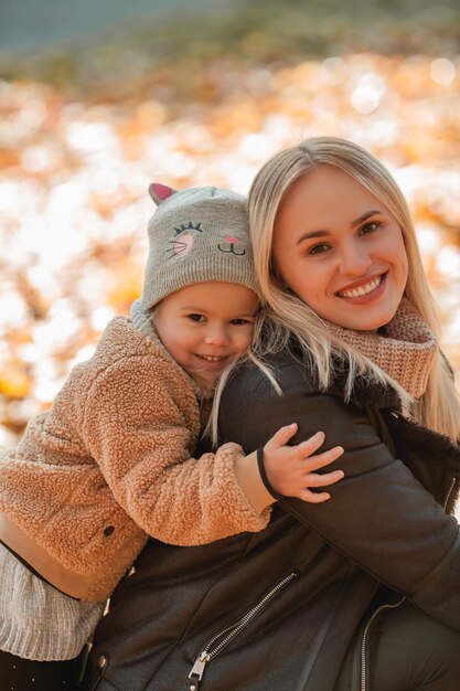 Happy mother and daughter are walking in the autumn park Beautiful family in warm clothes Fall