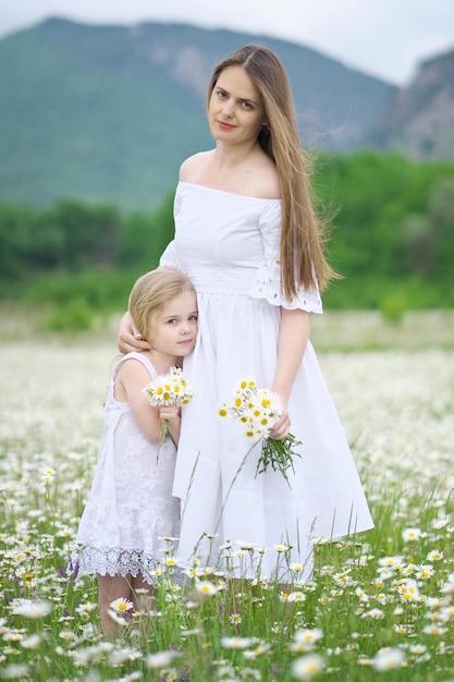 Happy mother and daughter in camomile meadow