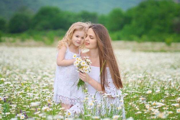 Happy mother and daughter in camomile meadow.