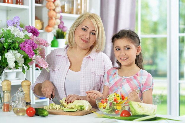 Happy mother and daughter cooking together at kitchen