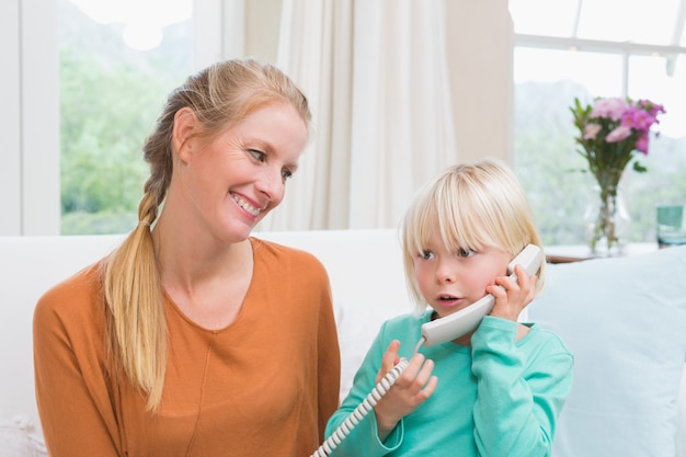 Felice madre e figlia sul divano al telefono