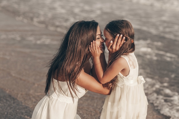 happy mother and daughter enjoying sunny day on the beach