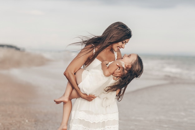 happy mother and daughter enjoying sunny day on the beach