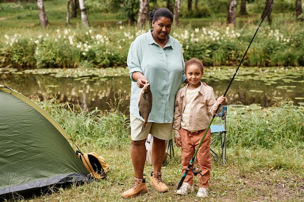 Happy mother and daughter fishing together looking at camera