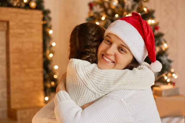 Happy mother and daughter hugging each other and congratulating with Christmas