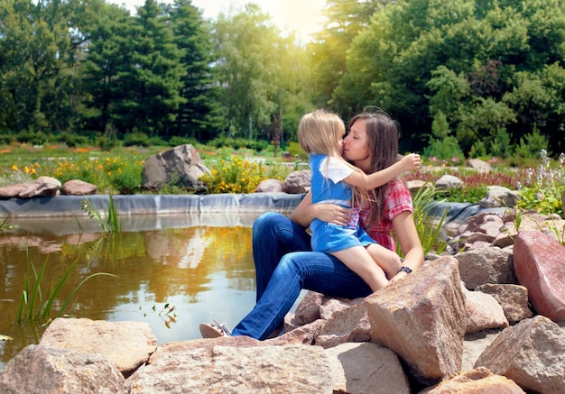 Happy mother and daughter hugging near a pond