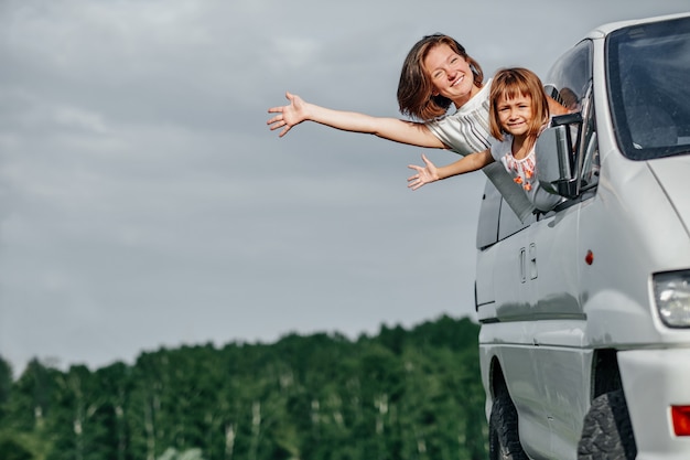 Foto felice madre e figlia che guardano fuori dalle finestre e si godono il viaggio. famiglia che viaggia in auto.