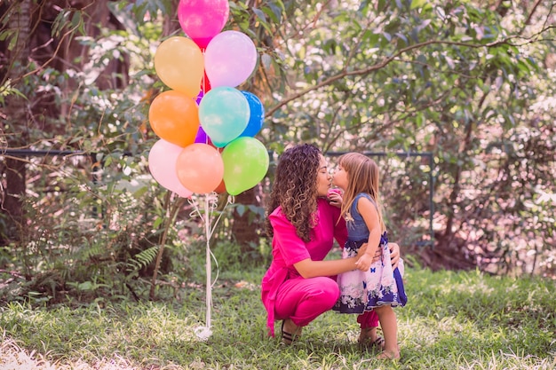 Happy mother and daughter in the park with balloons.