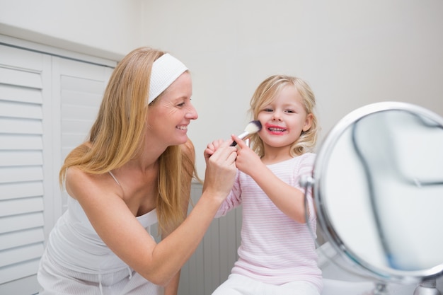 Happy mother and daughter playing with make up